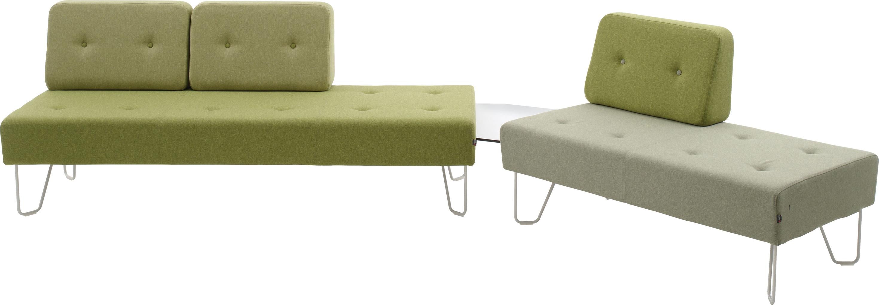 Zwei grüne Sofamodule mit integrierter Ablagefläche.