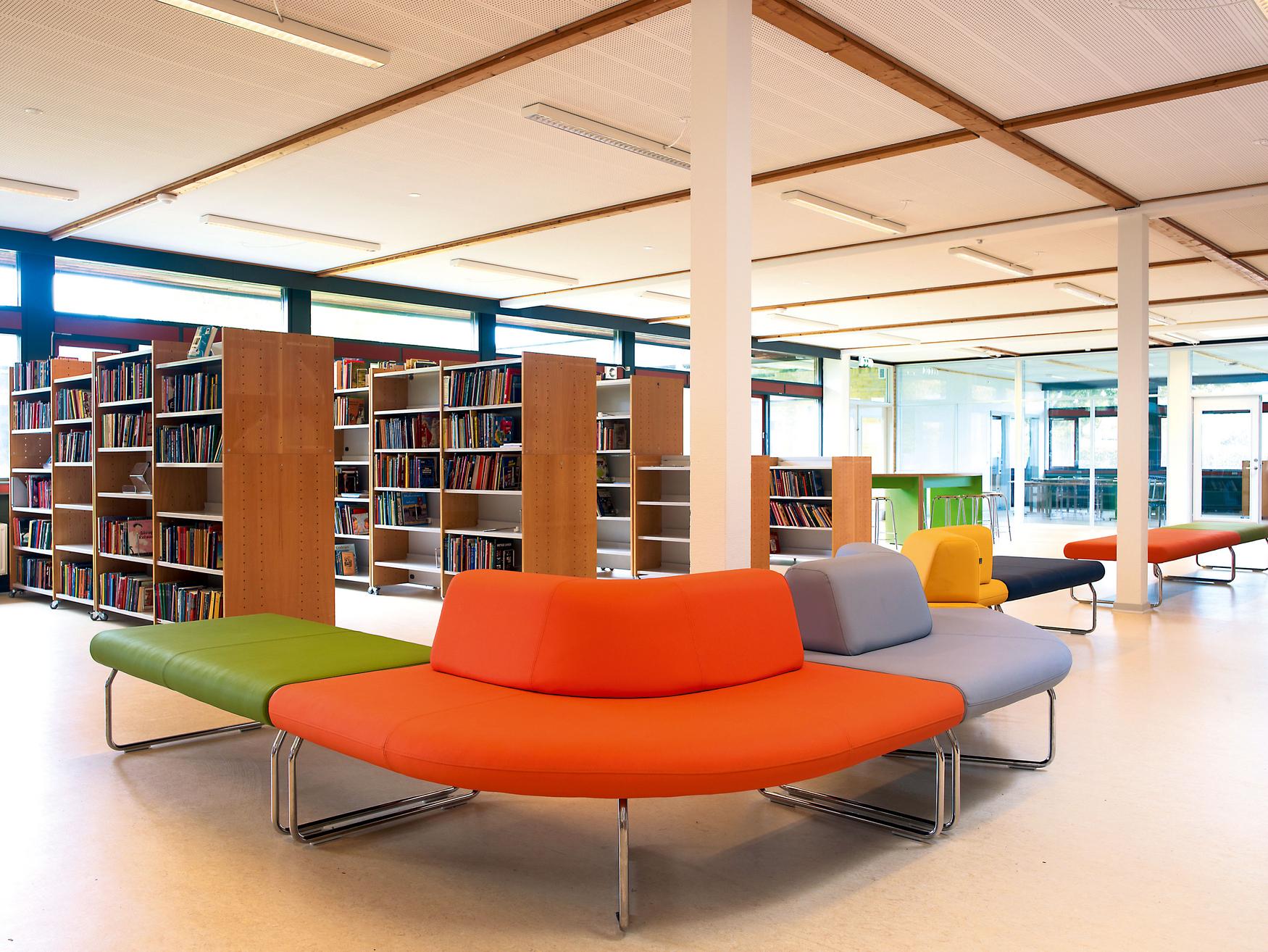 Sitzlandschaft in bunter Bibliothek mit Regalen und Tischen.