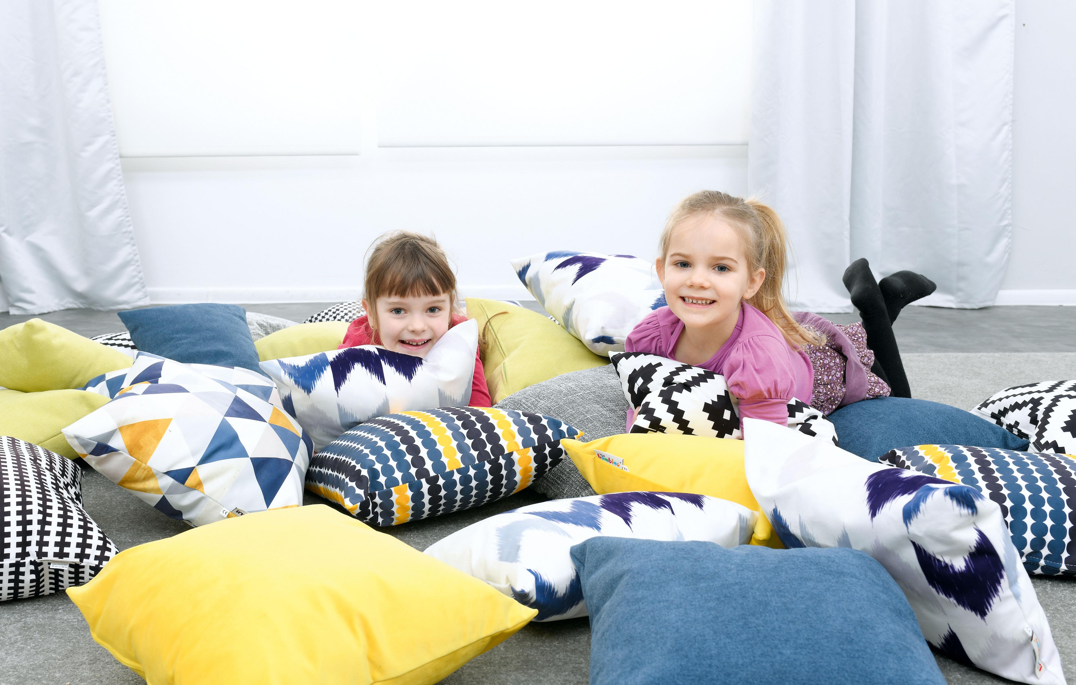 Kinder liegen auf bunten Kissen für Sitzlandschaft.