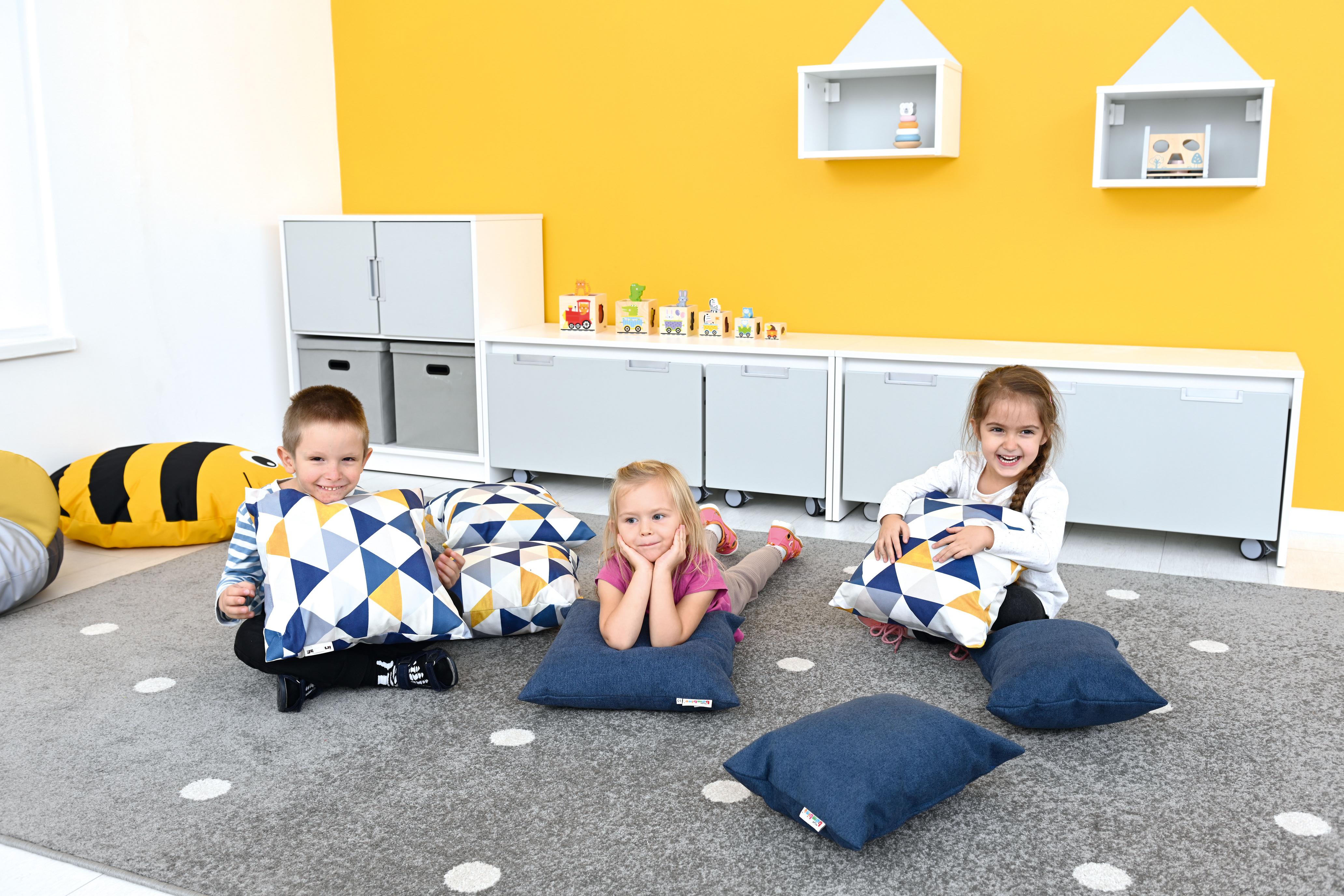 Kinder genießen Kissen für Sitzlandschaft im Gruppenraum.
