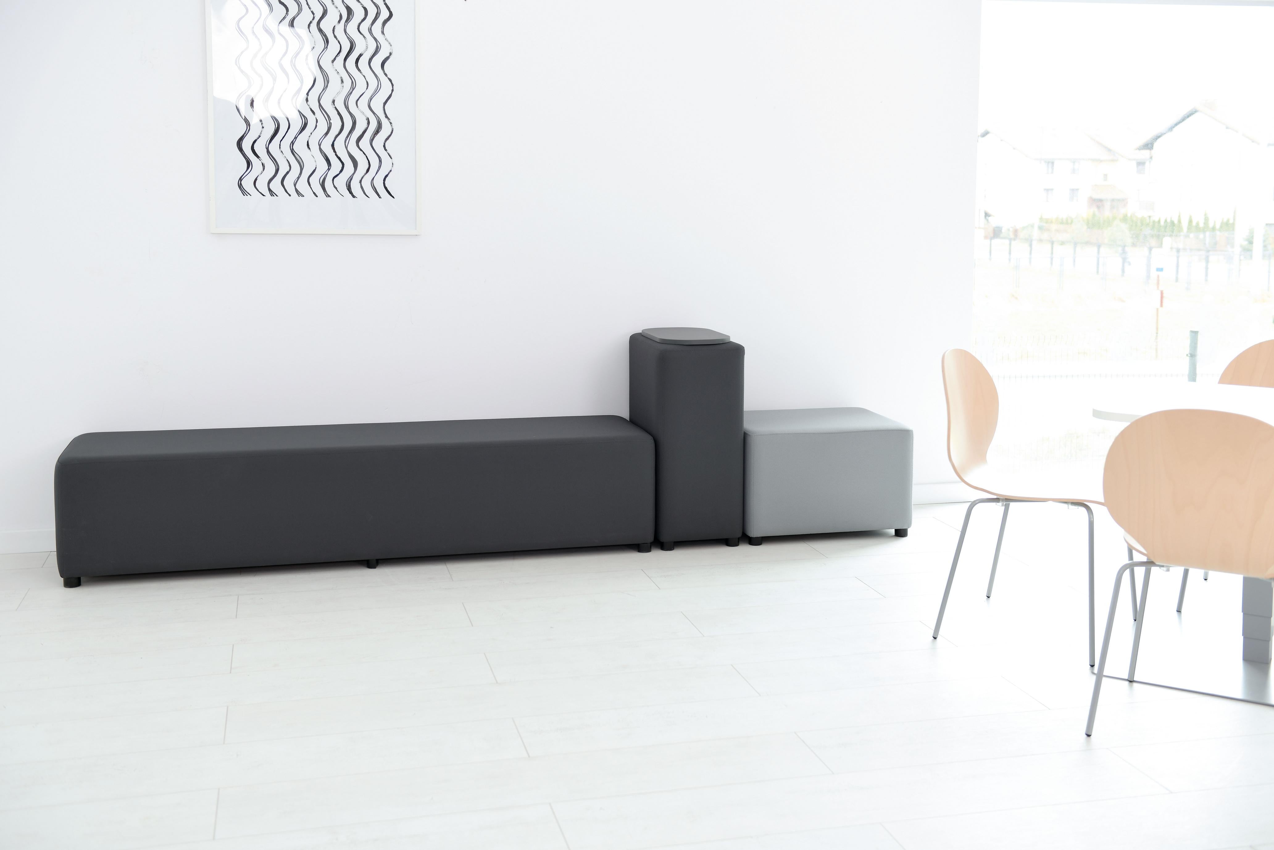 Modulare Sitzlandschaft im minimalistischen Raum mit Stühlen.