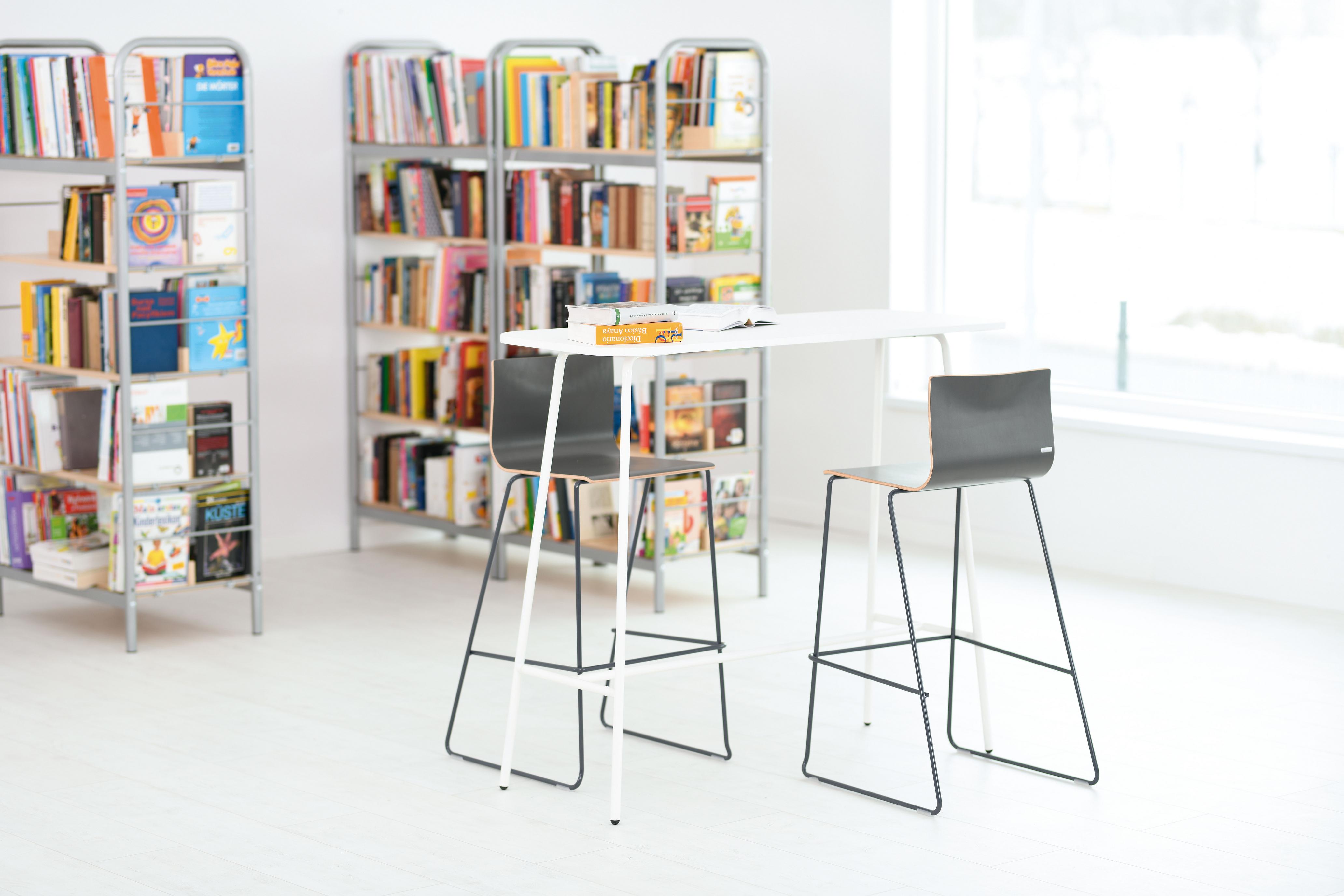 Hochtisch mit zwei Stühlen im modernen Leseraum.