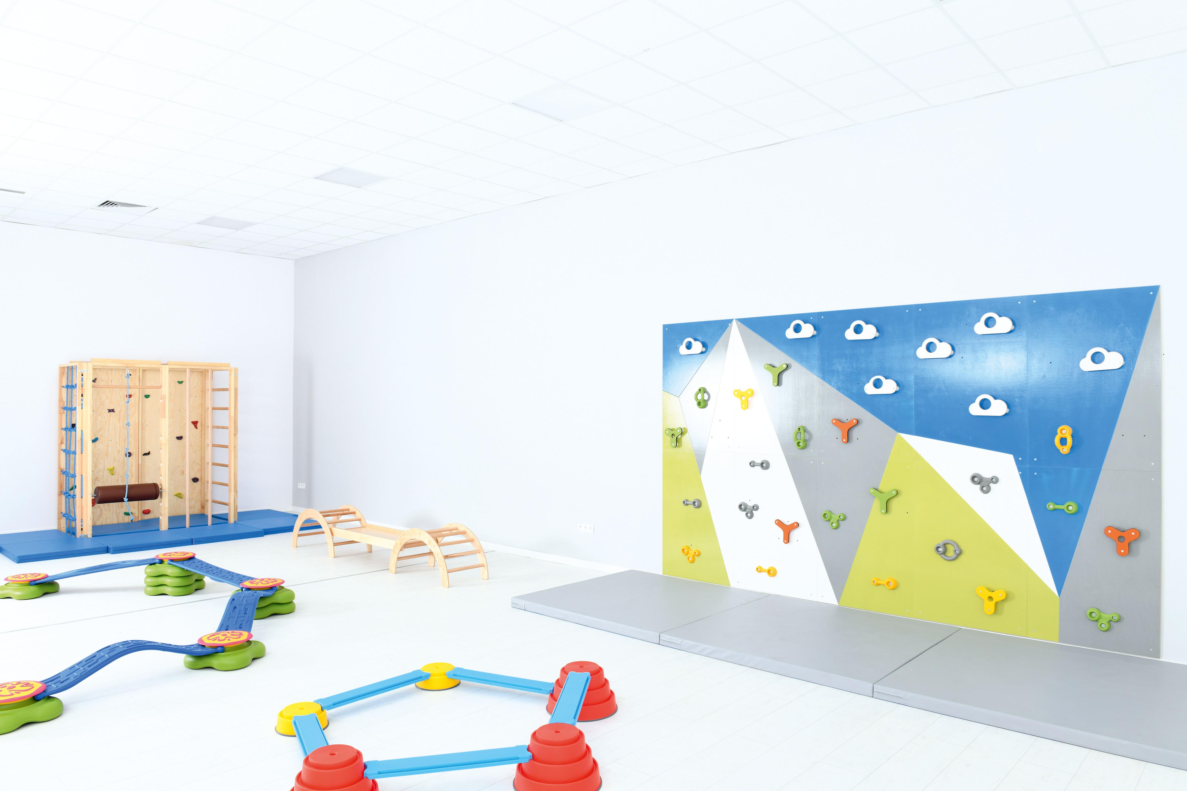 Bunte Kletterwand und Spielgeräte in Sporthalle.