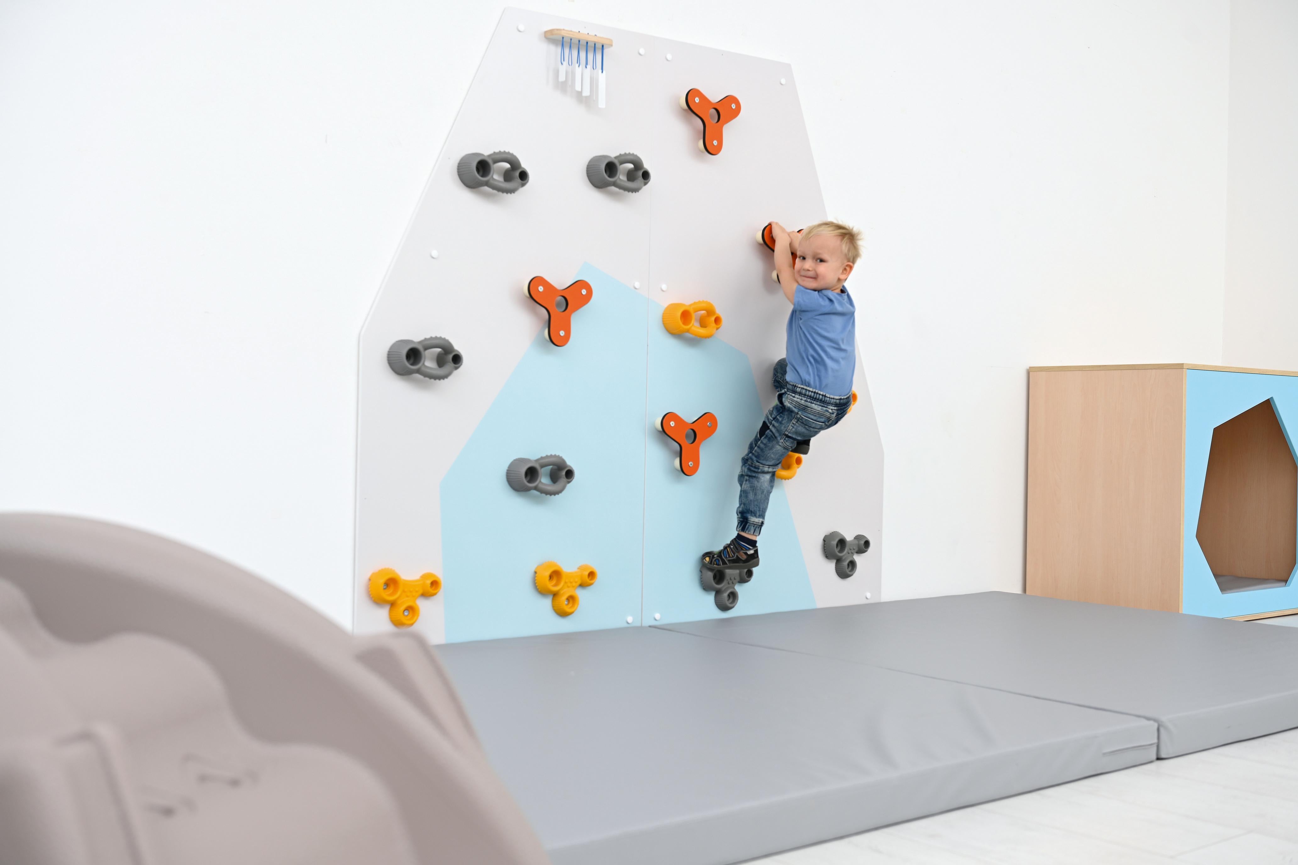 Kind klettert an bunter Kletterwand für Kita.