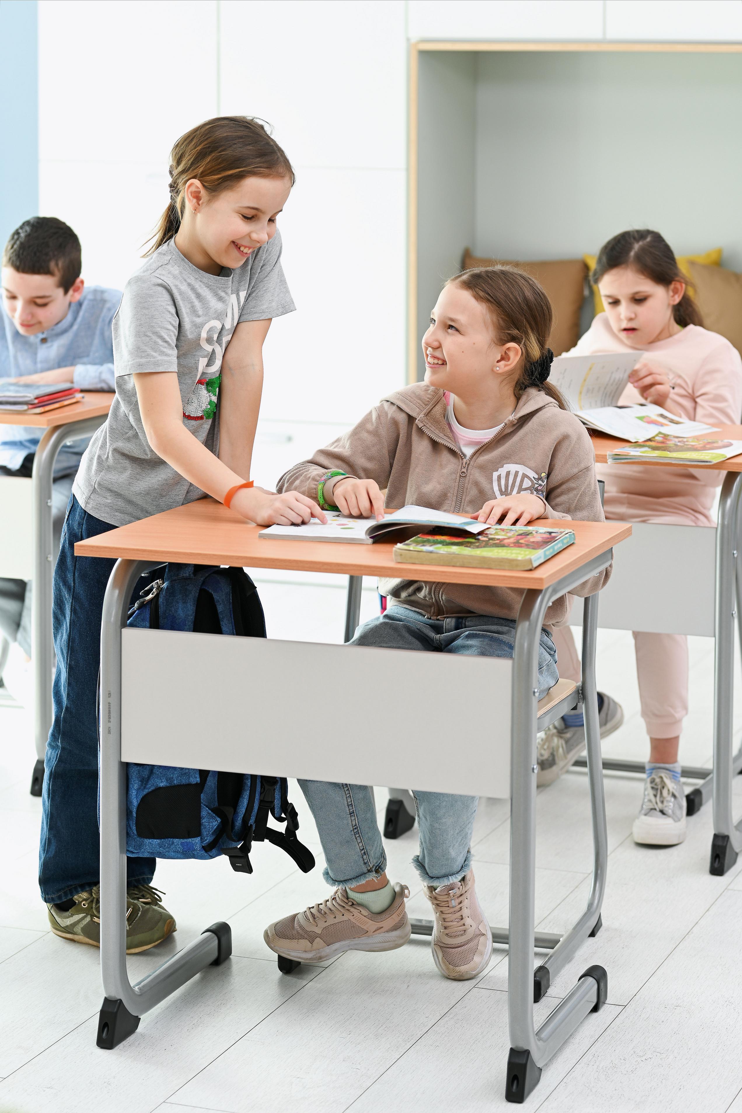 Kinder sitzen auf Schülerstuhl im Klassenzimmer.