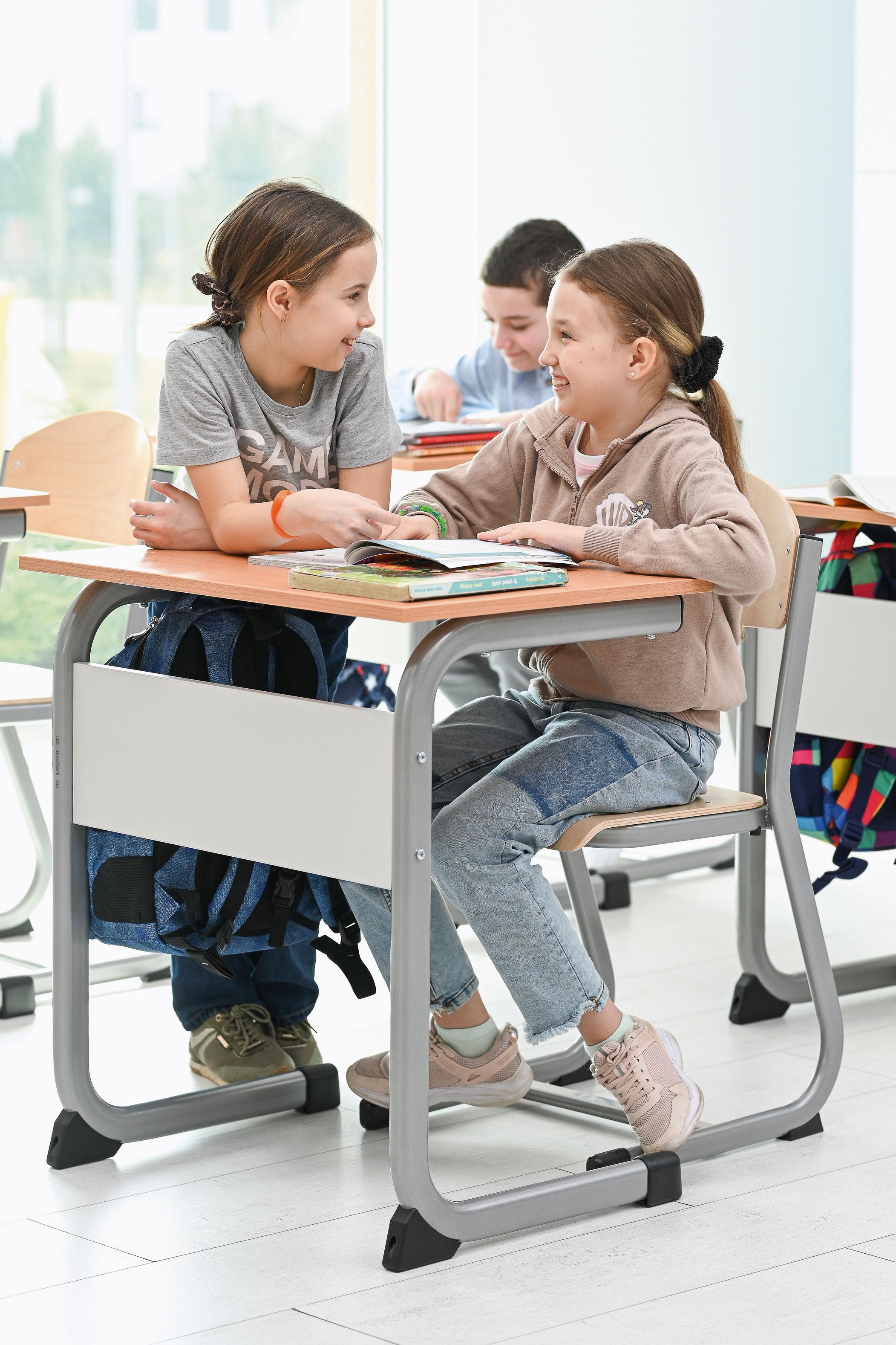 Kinder sitzen auf Schülerstühlen, lernen gemeinsam im Klassenzimmer.