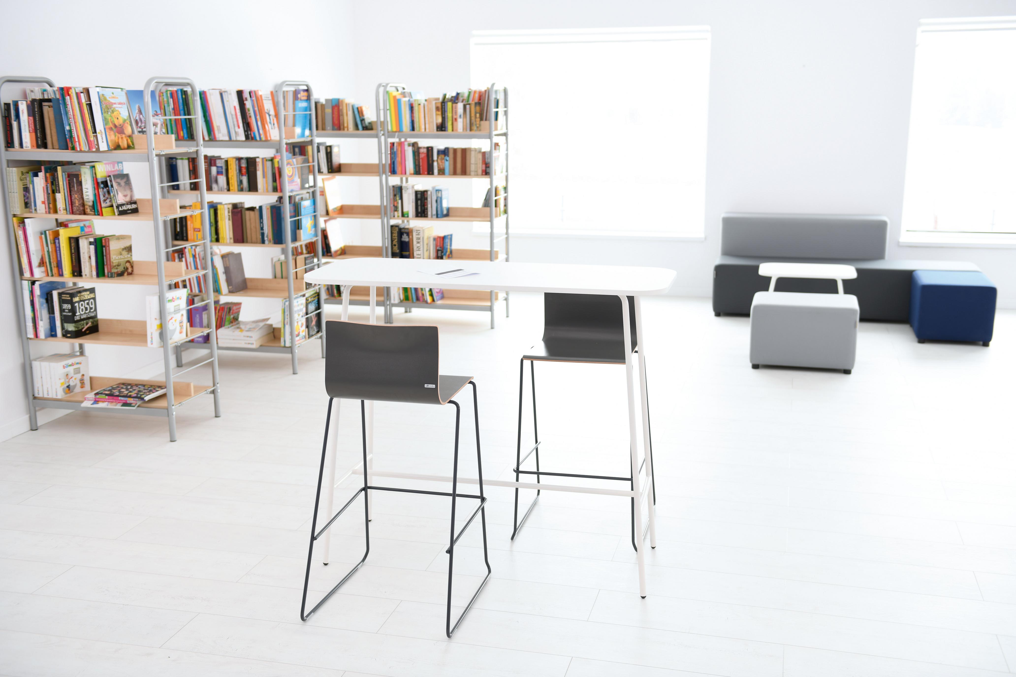 Moderner Raum mit Barhockern und Bücherregalen.